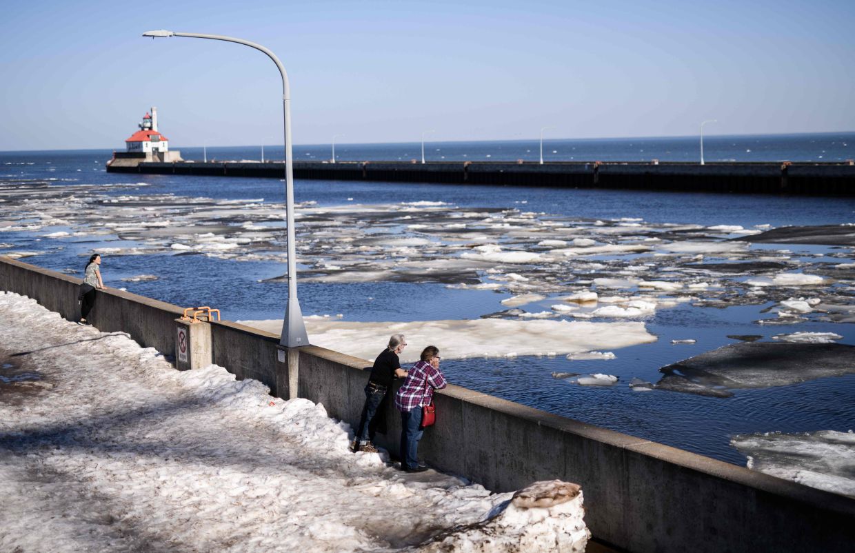 People watching as chunks of ice flow from Duluth Harbor out into Lake Superior.