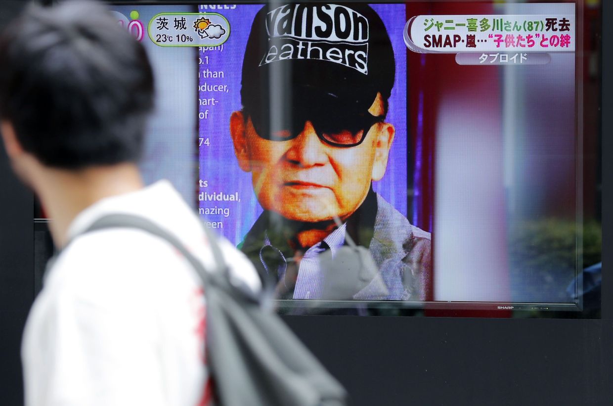 A filepic of a passer-by watching news reporting on the death of Johnny Kitagawa, founder of Johnny's talent agency, in Tokyo, July 10, 2019. Photo: AP