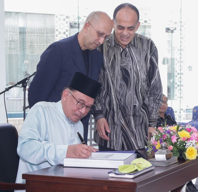 Anwar signing on the “Orientalist Painting: Mirror or Mirage?” book as Syed Mokhtar (right) and Syed Mohamaed Albukhary look on at the Islamic Arts Museum in Kuala Lumpur on Friday. — IZZRAFIQ ALIAS/The Star