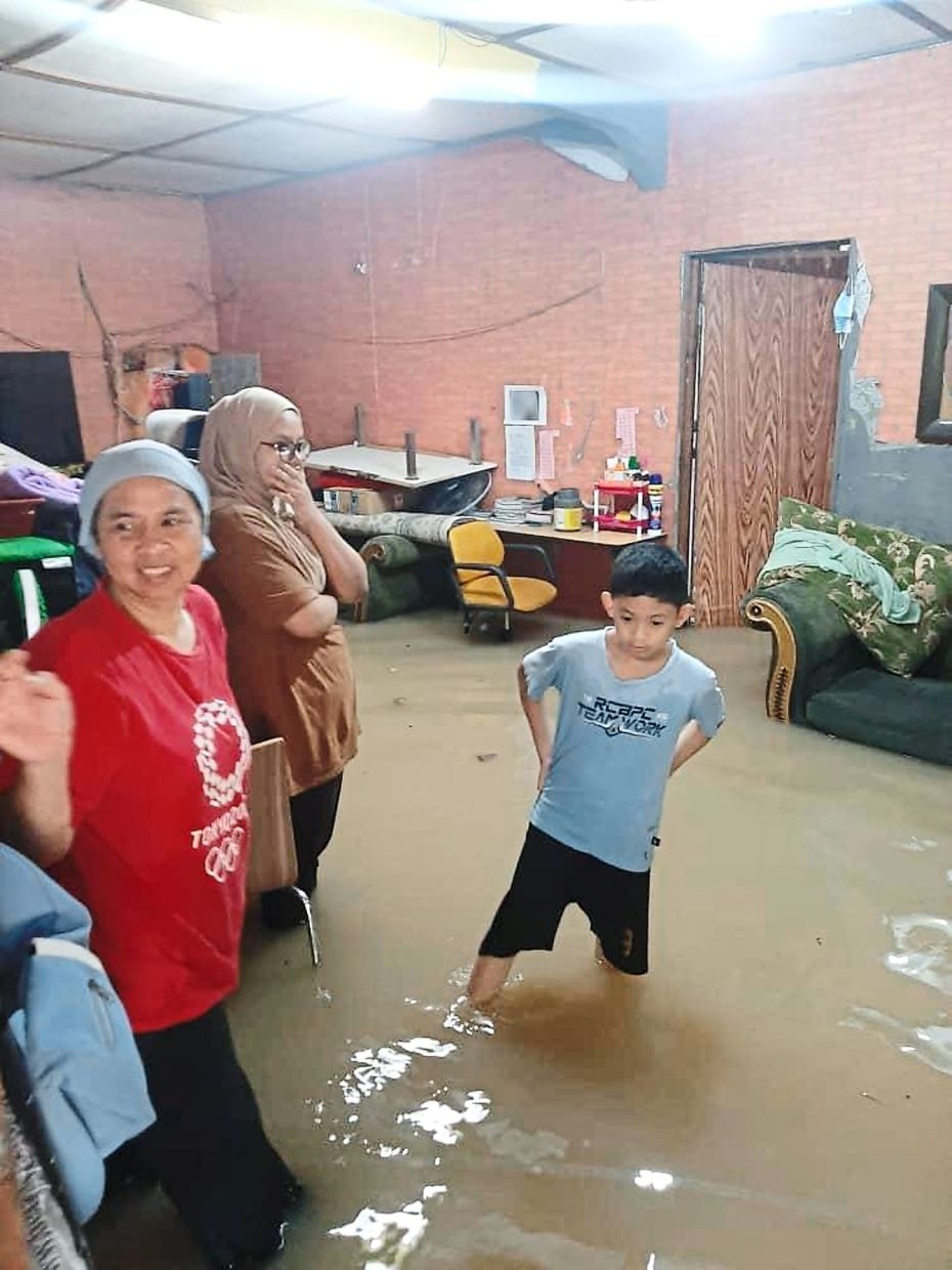 All ruined: Family members looking helplessly as their furniture and belongings are submerged in Kg Kubu Gajah, Shah Alam.