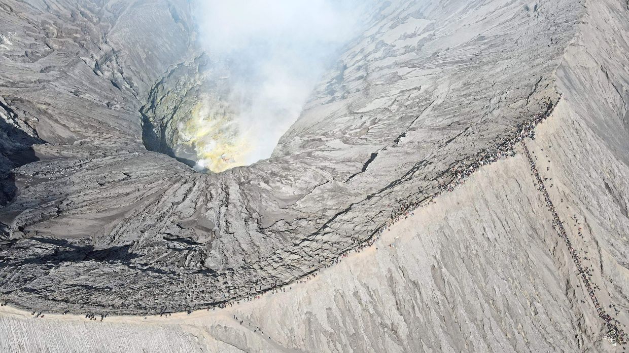 Smoking crater: This aerial picture shows people gathering to present offerings to Mount Bromo in Probolinggo, East Java. — AFP