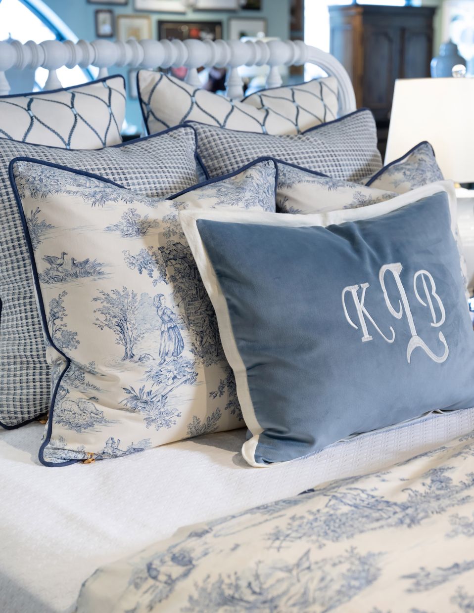 A classic blue and white traditional toile is the focal fabric for this bedding look that combines creams, whites, and multiple shades of blue for a refined yet relaxed bed. 