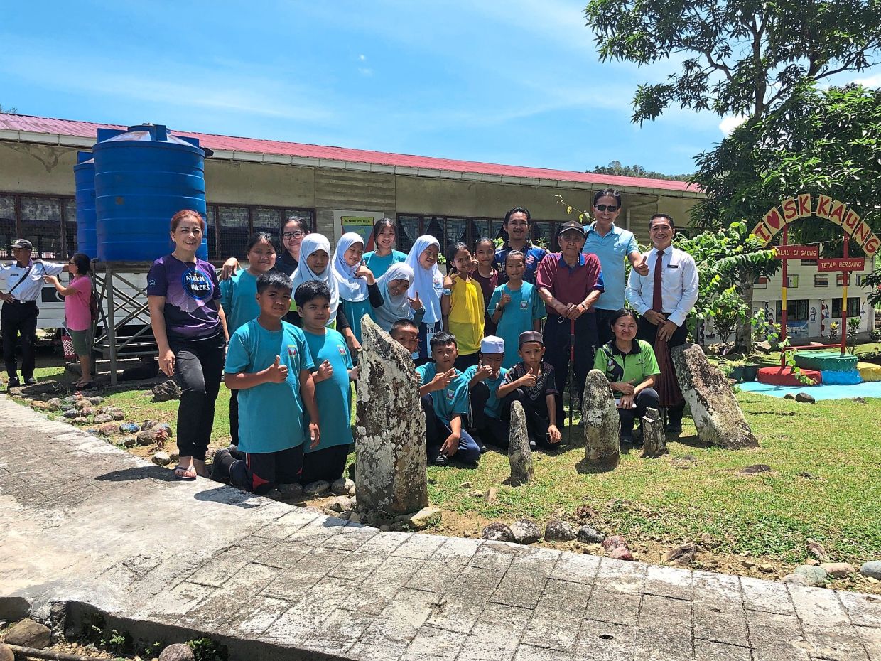 (Standing, from right) School principal Jimri, the writer and Pak Bondion, together with teachers and students, beside the five legendary stones.