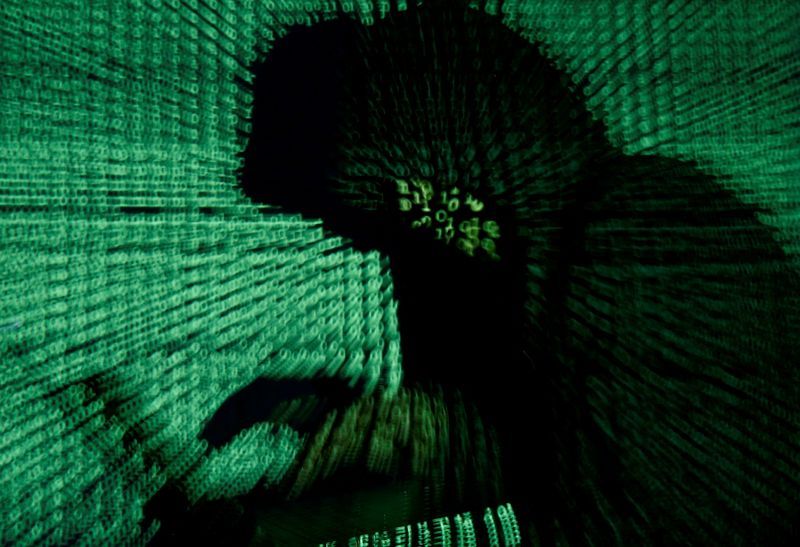 FILE PHOTO A man holds a laptop computer as cyber code is projected on him in this illustration picture taken on May 13 2017. REUTERSKacper Pempel