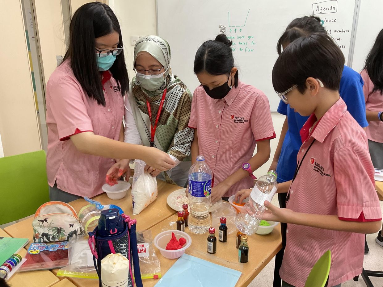 A TIS teacher educating students on how to create craft using discarded materials.