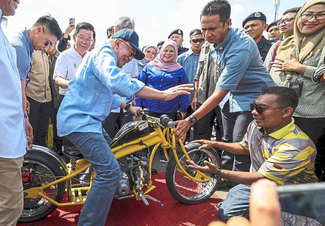 Hot ride: Anwar sitting on a modified motorcycle during a visit in conjunction with Program Sentuhan Kasih Desa Peringkat Negri Pulau Pinang in Kepala Batas. — Bernama