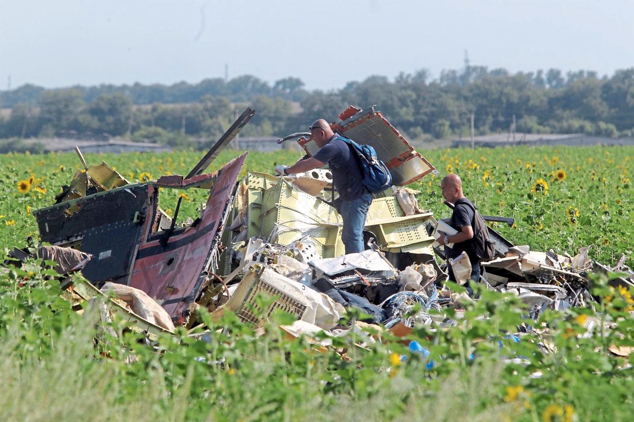 Seeking clues: The Malaysian MH17 investigation team hard at work at one of the crash sites near Grabovo, Ukraine.