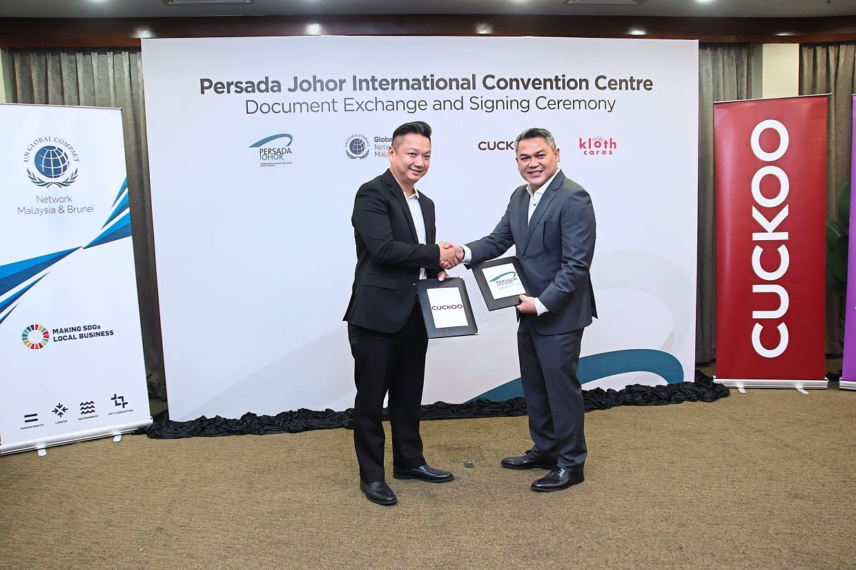 Bareng (right) exchanging documents with Cuckoo International sales vice-president Michael Lee.