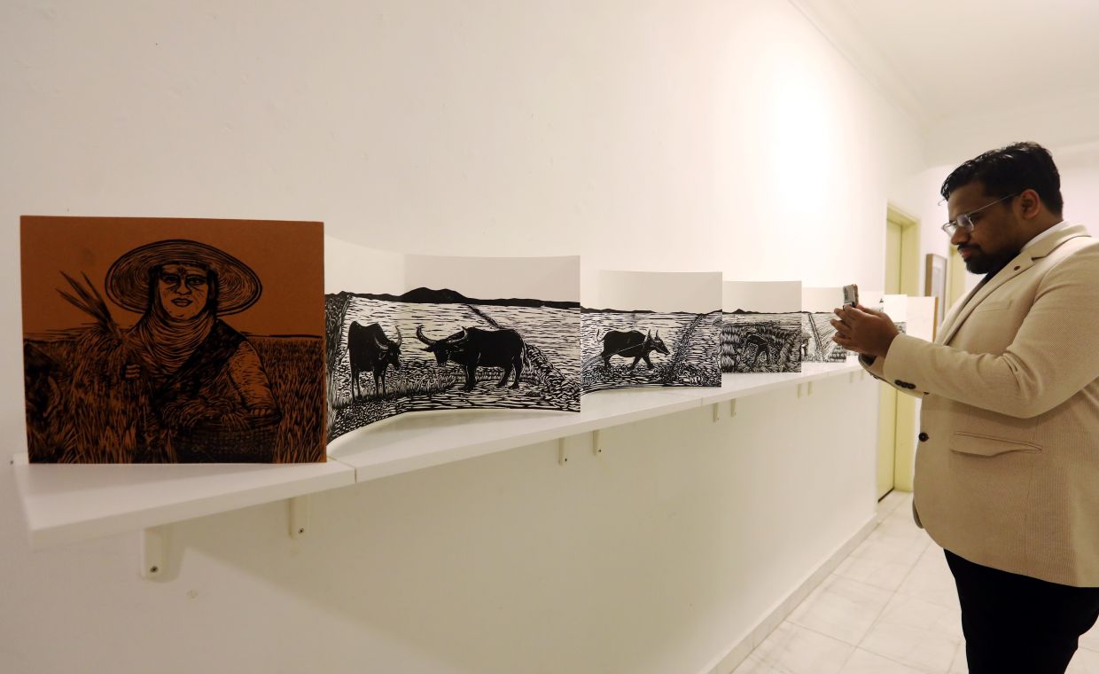 A gallery visitor takes a closer look at Sabah-based printmaker Rizo Leong 'Tadau Kaamatan' art book, which measures 4.3m in length. Photo: The Star/Azlina Abdullah 