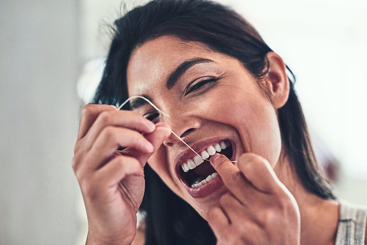 Flossing helps get rid of the leftover food and bacteria stuck in the hidden spots between your teeth. — AFP