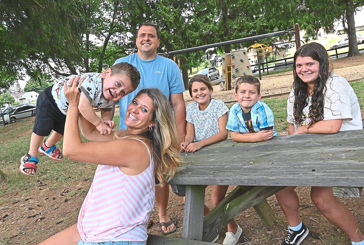 Jessica lifts Hank in the air, as Steve (standing) and their other children (seated, from left) Juliette, 10, Zach, 6, and Violet, 13, look on.