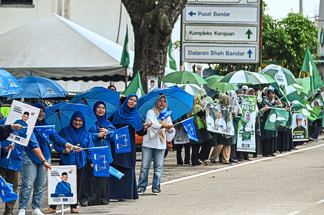 Barisan Nasional and PAS members trying to attract voters outside a polling station in Kuala Terengganu on election day last month. — Bernama