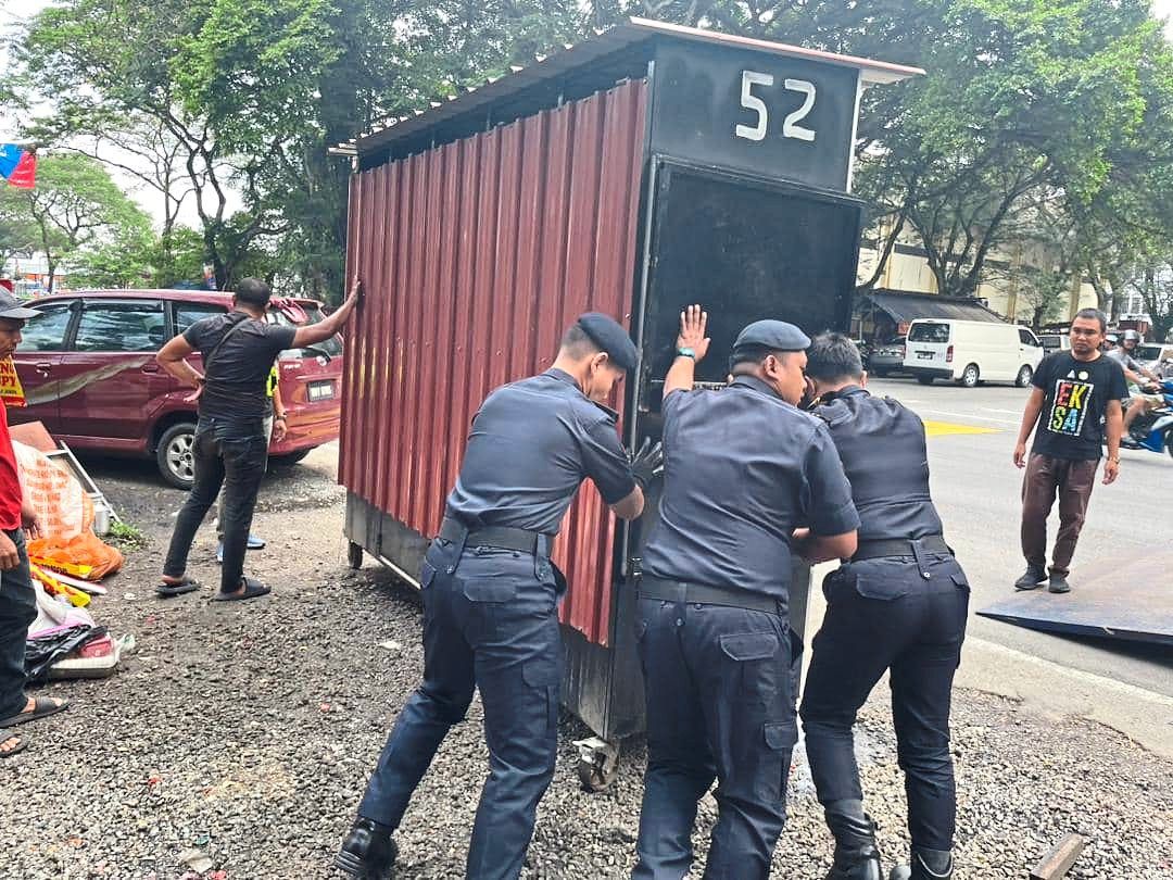 MPS officers confiscating a kiosk left by the road after operation hours.