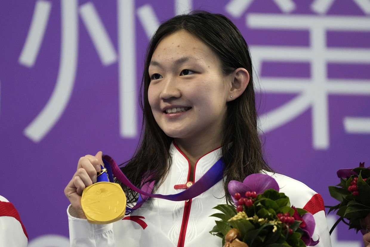 China's Li Bingjie celebrates with her gold medal during the victory ceremony for the women's 1500 meter fast heats at the 19th Asian Games in Hangzhou, China, Sunday, Sept. 24, 2023. - AP