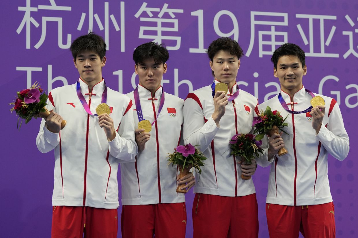 Gold medalist Team China celebrates on the podium during the victory ceremony for the men's 4x100m medley relay swimming at the 19th Asian Games in Hangzhou, China, Tuesday, Sept. 26, 2023. - AP