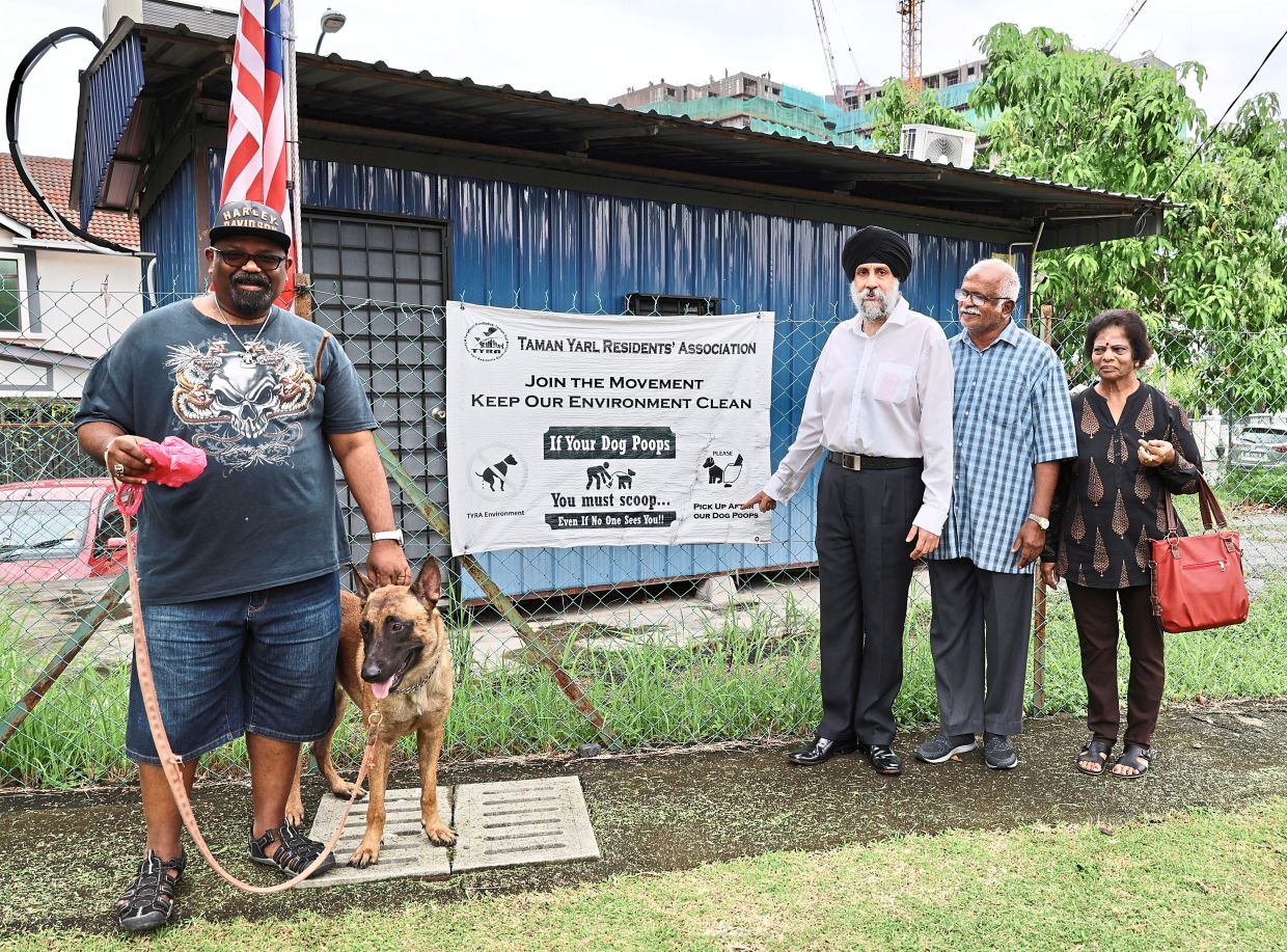 (From left) Taman Yarl resident Alvin Thayaparan with his 19 month old Belgian Malinois, Rasa, residents association president Datuk Rabinder Singh, Rukun Tetangga chairman K. Balarandran and his wife, Sathia Poovathy standing in front of the poster reminding residents to pick up after their pets.