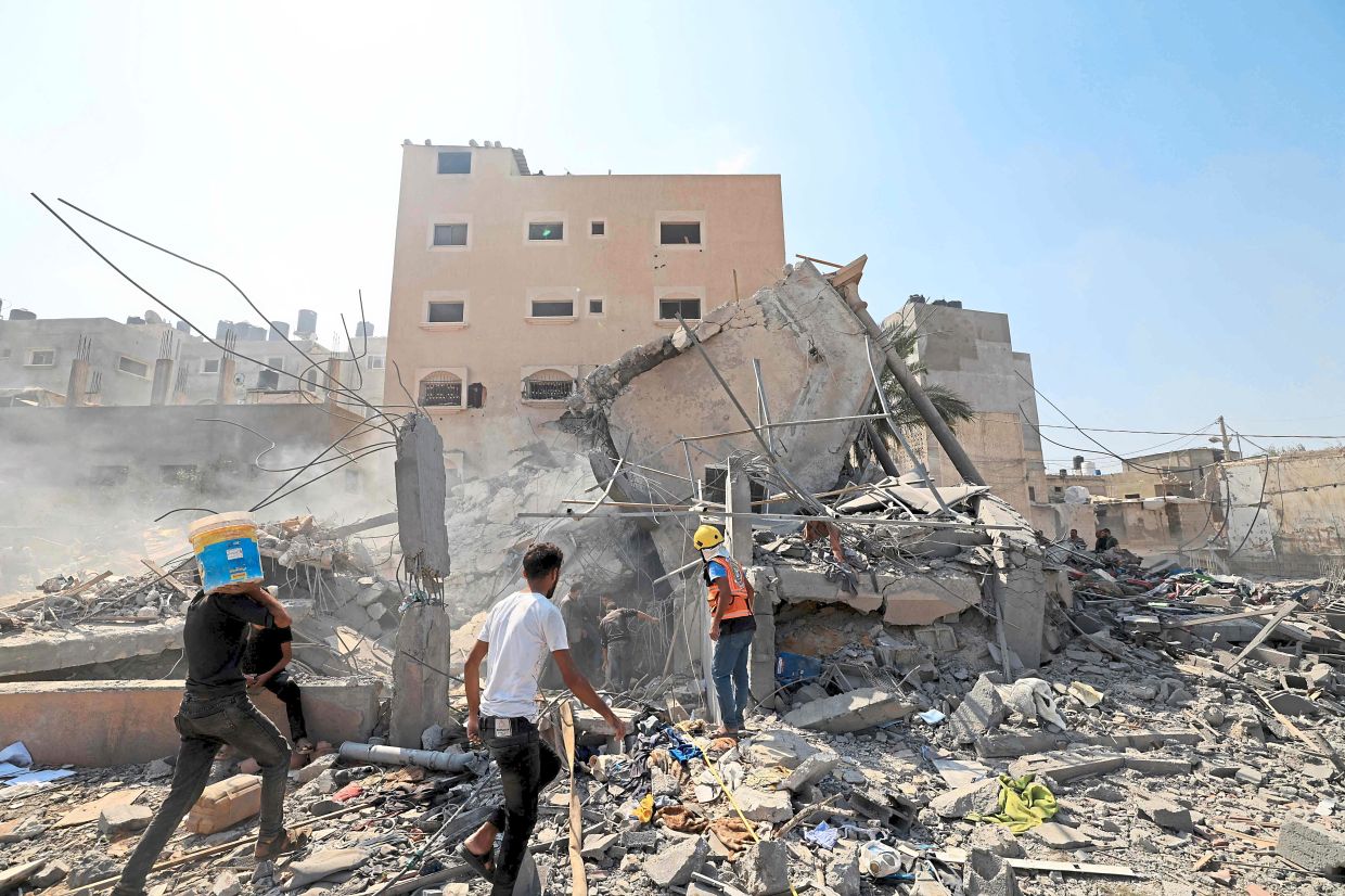 Bombarded: Palestinians surveying the rubble of a collapsed building following an Israeli strike yesterday in Khan Yunis in the southern Gaza Strip. — AFP
