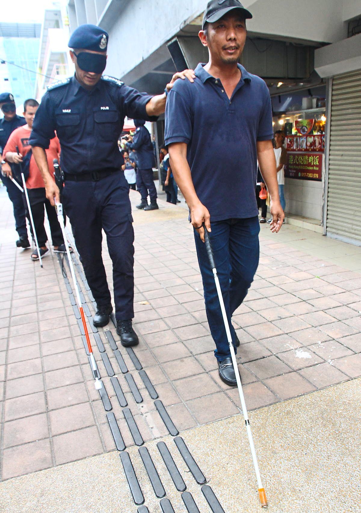 Mohd Shuhaily seems to have always taken a slightly unusual path – here he is (left) when he was Kuala Lumpur police chief discovering the problems of being blind in the city. — Filepic/Sin Chew