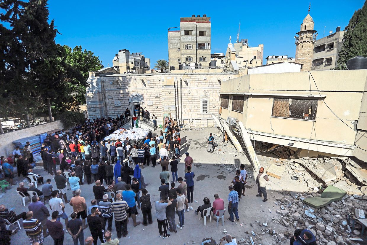 Relatives attend the funeral of Christian and Muslim Palestinians who were sheltering at a Greek Orthodox church in Gaza City, killed in Israeli airstrikes that hit it on Thursday. The Israeli military said it was targeting a Hamas command centre nearby. — AP