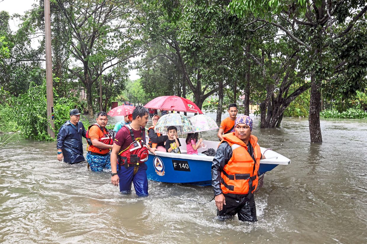 Rescue mission: Civil Defence members ferrying flood victims in Kampung Alur Bunut, Batu Buruk, Terengganu. — Bernama