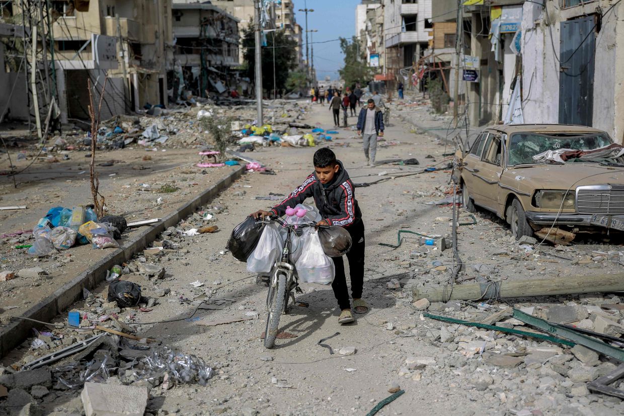 A boy carrying whatever he could salvage on his bicycle as Palestinians leave Gaza City to safer areas in the south on Nov 25, the second day of a truce between Israel and Hamas. — AFP