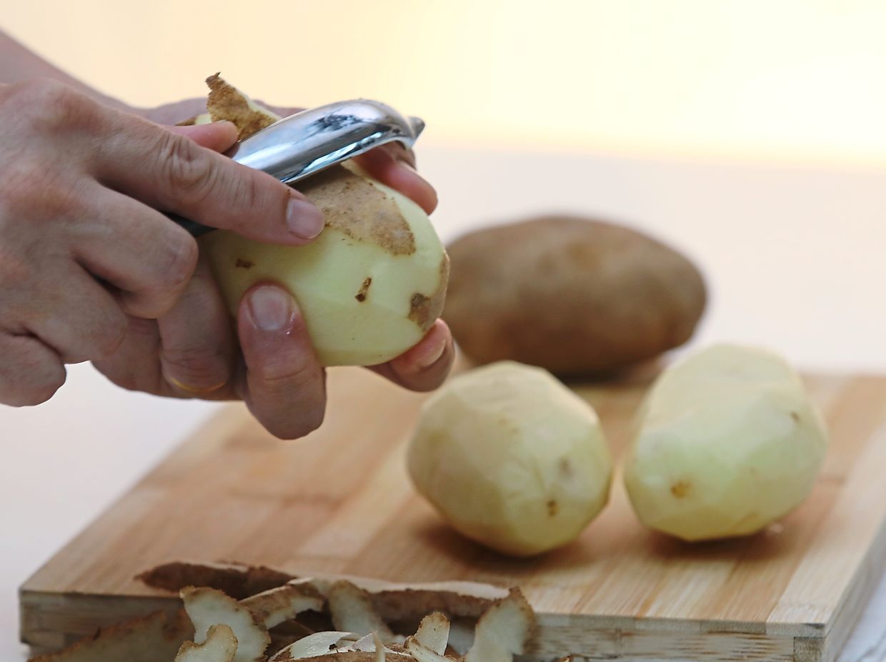 After peeling the potatoes, cut into halves. — Filepic