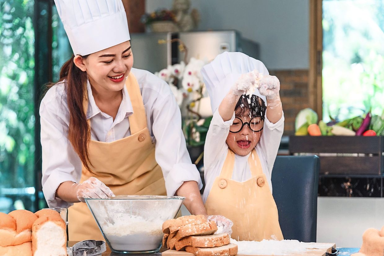 Young family cooking food in kitchen. Happy young girl with her mother mixing batter in the bowl.