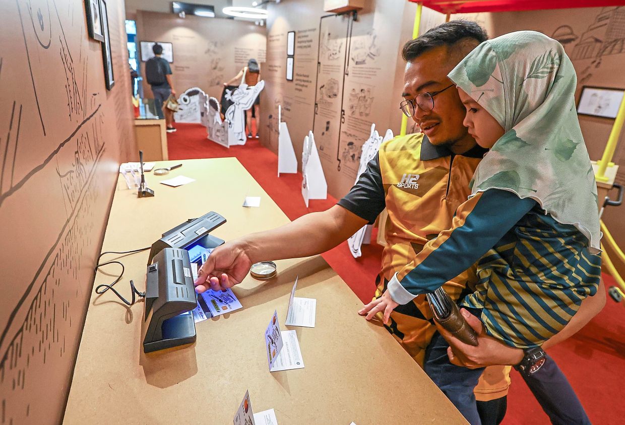 Hanizan with his daughter trying out some of the interactive displays at the exhibition.