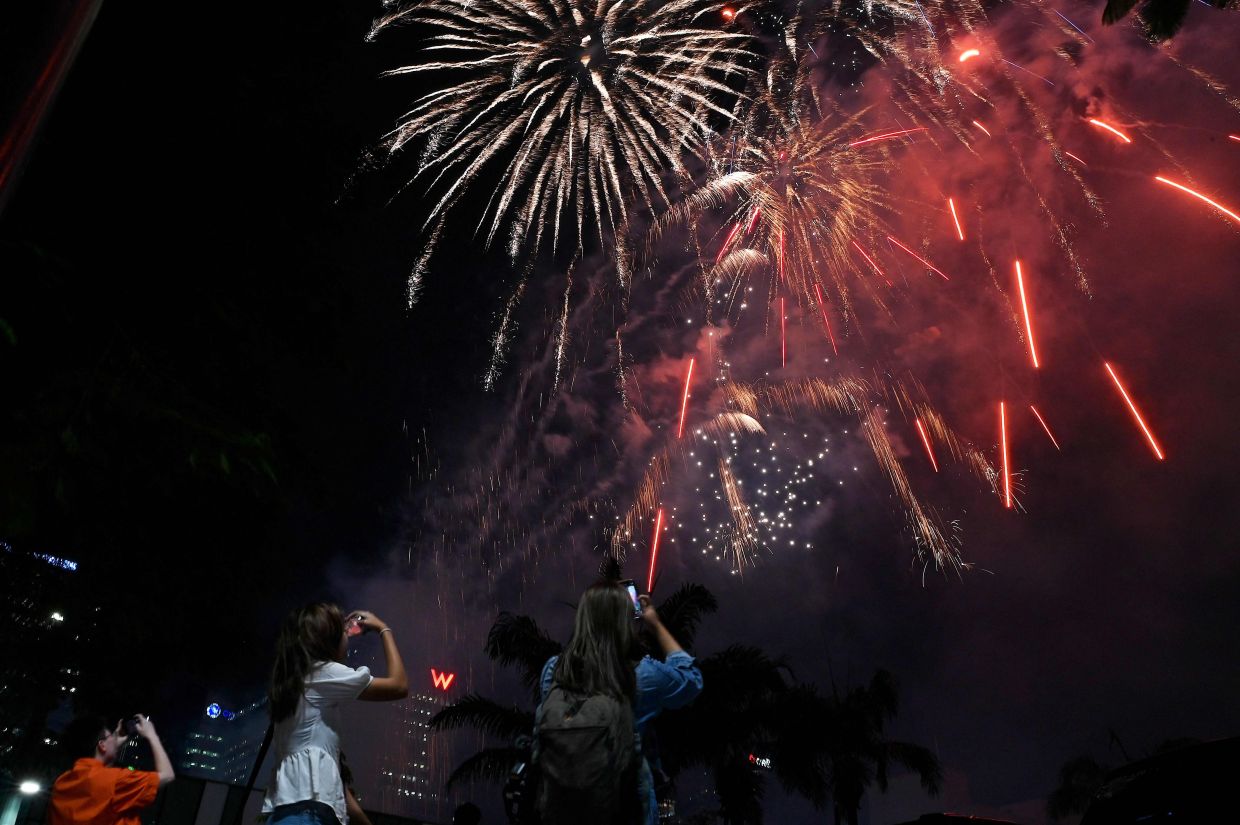 People watch fireworks illuminate the sky at Bonifacio Global City in Taguig, Metro Manila. - AFP