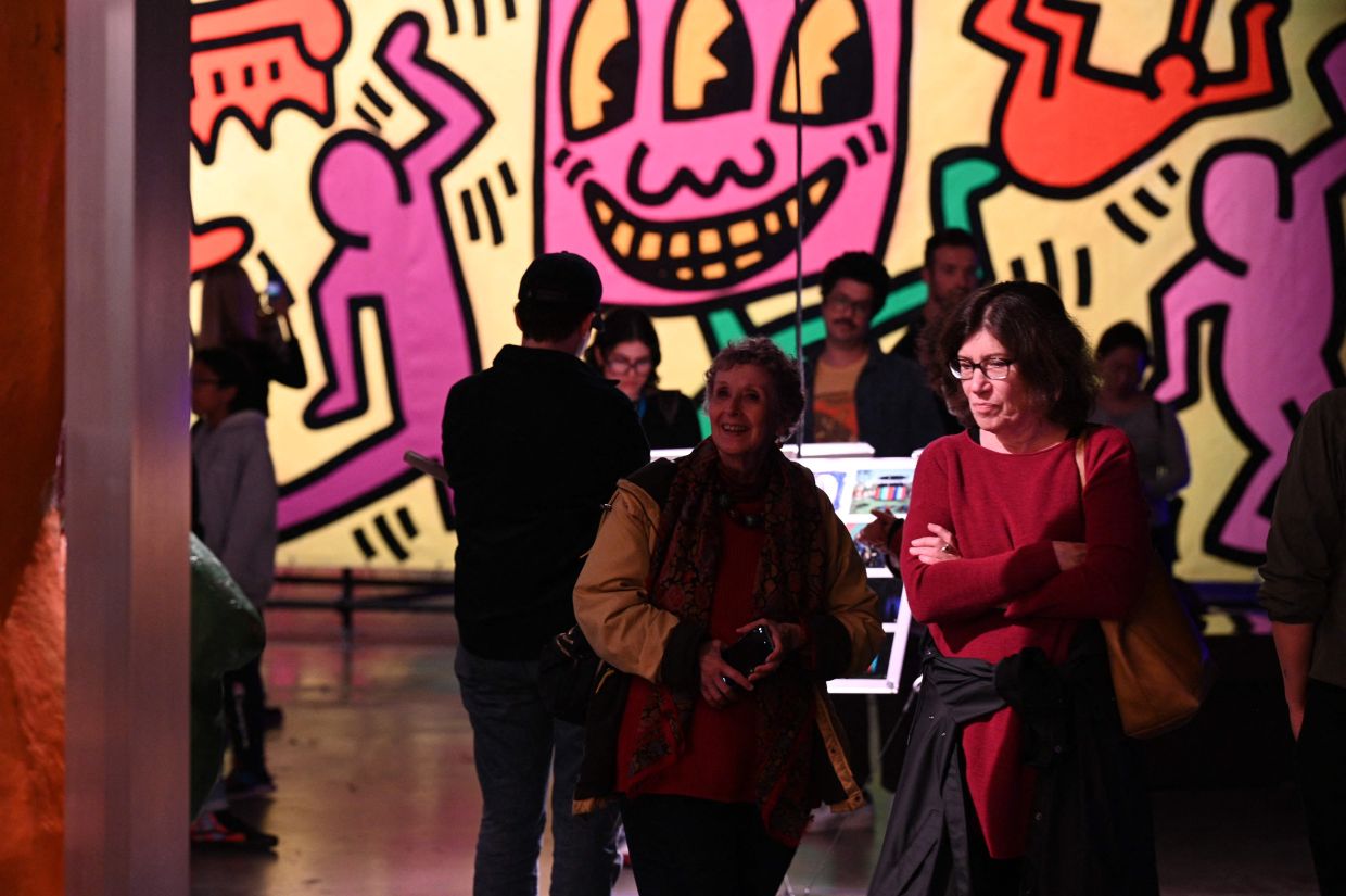 Visitors walk past a Keith Haring mural work at Luna Luna: Forgotten Fantasy. Photo: AFP