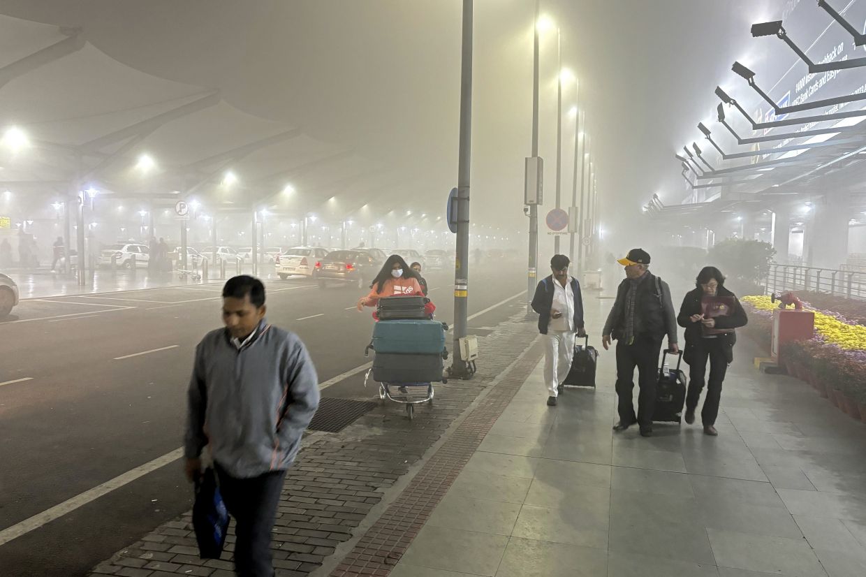 Travelers walk to get transport amidst early morning fog at the Indira Gandhi International Airport in New Delhi, India, Monday, Dec. 25, 2023. Dense fog enveloped Delhi on Monday, bringing visibility down to zero and severely disrupting air, rail and road transport. - AP