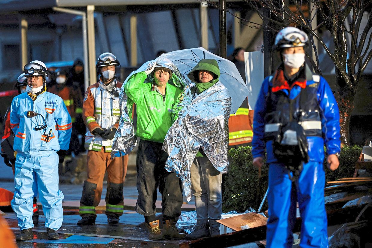 In shock: People covered in emergency blankets watching rescue operation following an earthquake in Wajima, Ishikawa prefecture. — Reuters