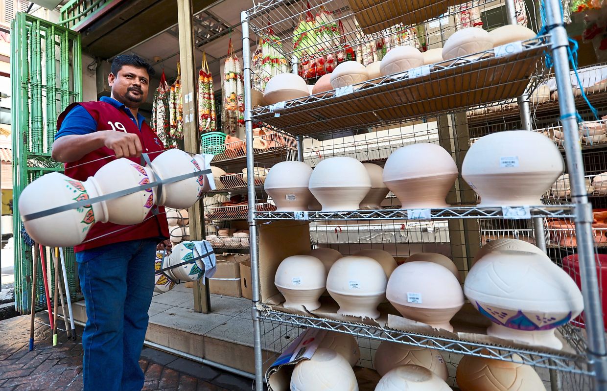 An employee bringing out claypots to display on racks.