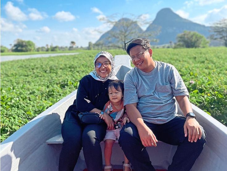 The writer with her husband and son taking a boat ride at Timah Tasoh with Bukit Chabang in the background