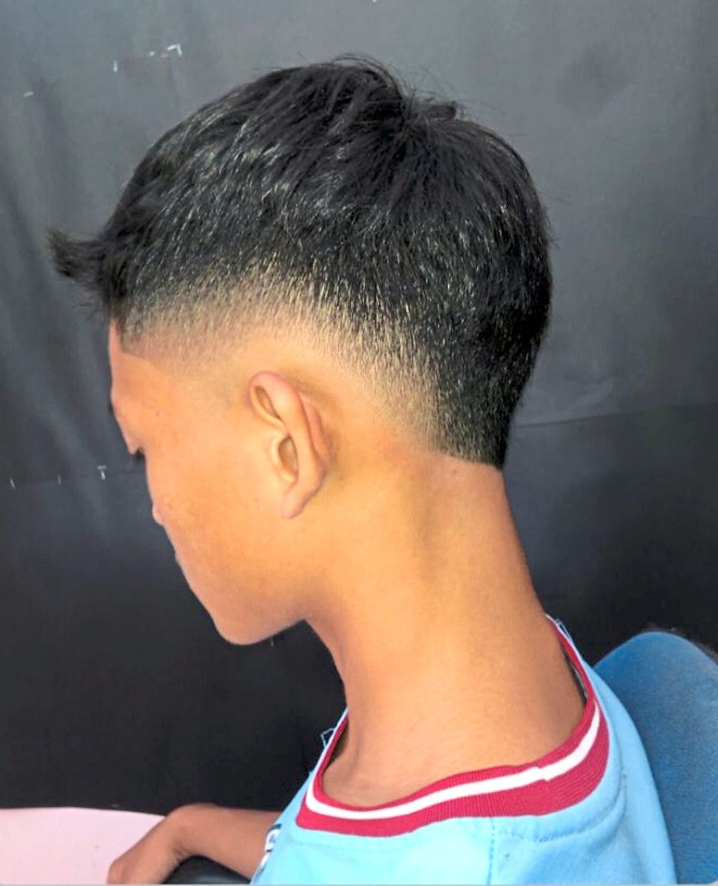 A student showing his new hairstyle done by Zulkifli.