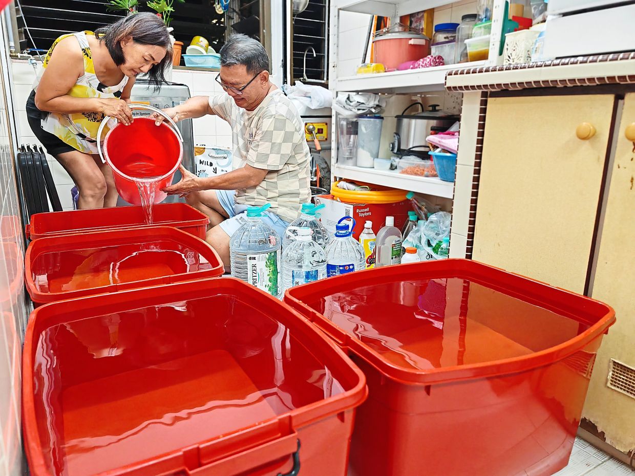 All set: Tan Guan Hin (right) and his wife Loo Soon Chin at their flat in Taman Lip Sin, Penang. The couple were busy preparing stored water for the water crisis. — KT GOH/The Star