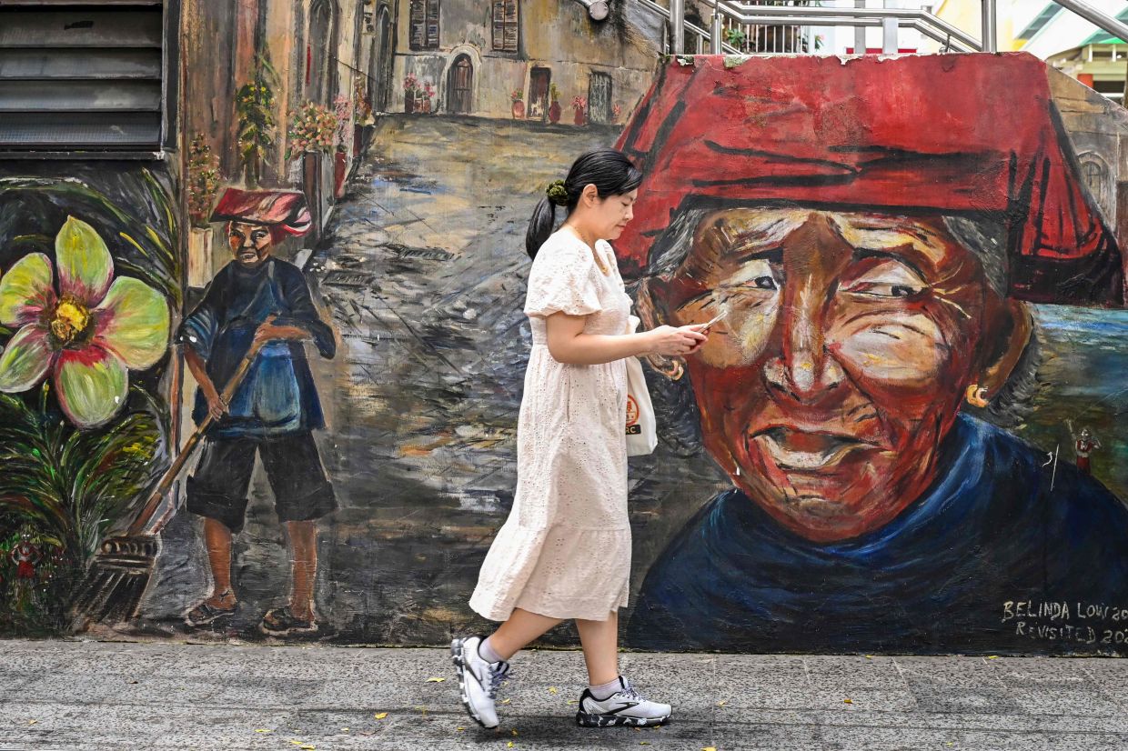A woman walks past a mural in Chinatown in Singapore. - AFP