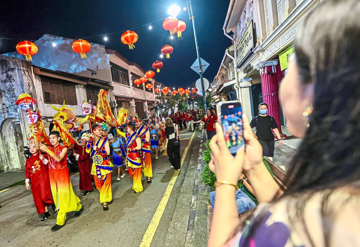 A spectator recording the procession with her handphone.