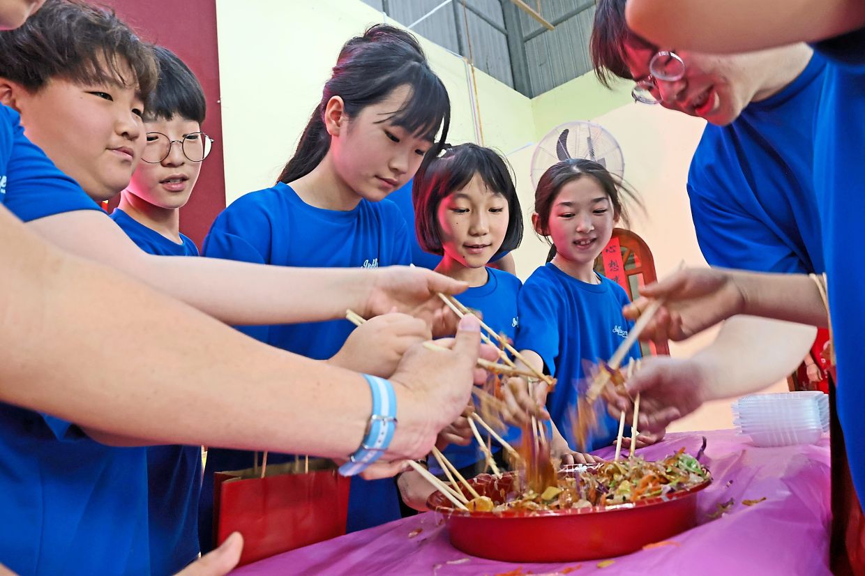 Korean teachers and exchange programme students tossing yee sang during a Chinese New Year celebration at SJK(C) Poay Wah.