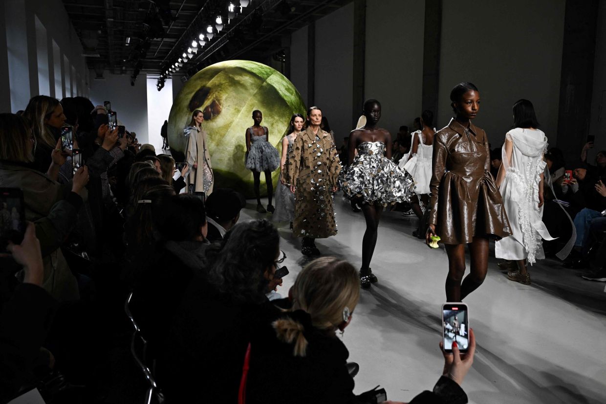 Models walk past a giant apple during the Cecilie Bahnsen runway show at Paris Fashion Week. Photo: AFP