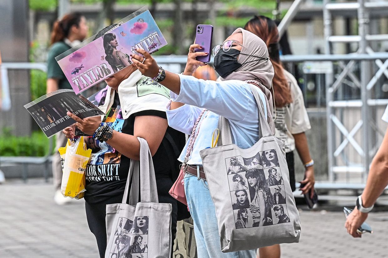 Swift’s fans, known globally as Swifties, taking photos as they arrive for the pop star’s Eras Tour concert at the National Stadium in Singapore on Thursday. — AFP
