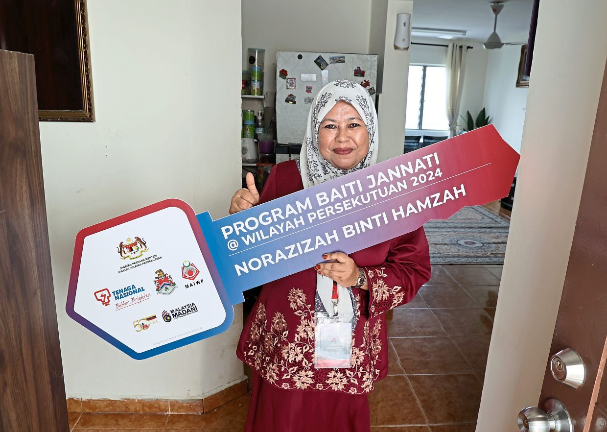 Norazizah with a mock key that represents her home ownership.
