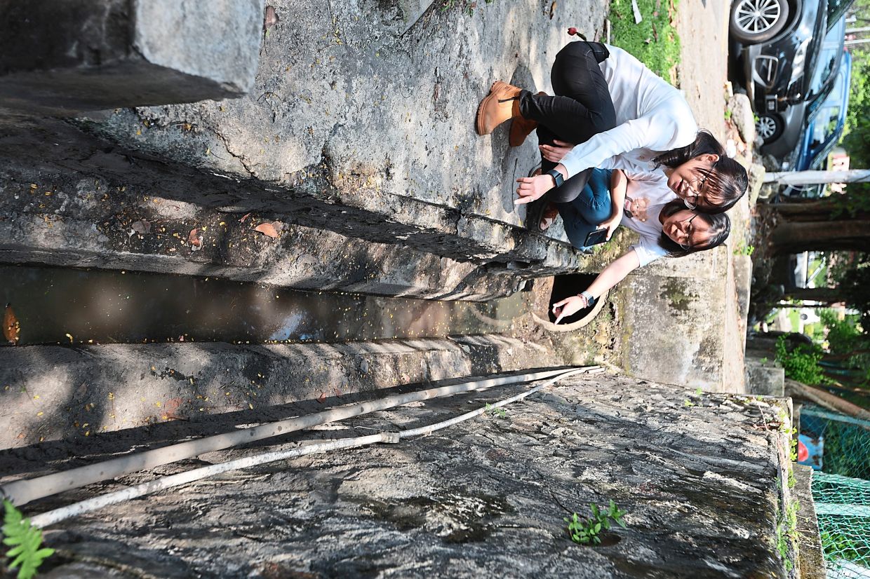 Siew Ki (left) and Suzanah inspecting a drain around the Taman Universiti Indah morning market two weeks after the clean-up operation.
