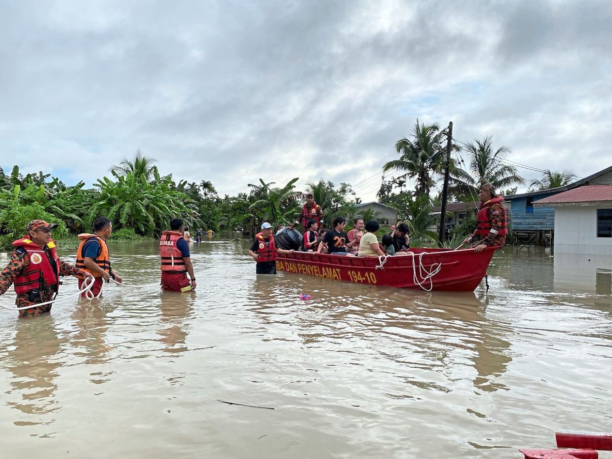 Fire and Rescue Department personnel helping to evacuate residents of Kampung Sinar Budi Baru during the flash flood on March 2.