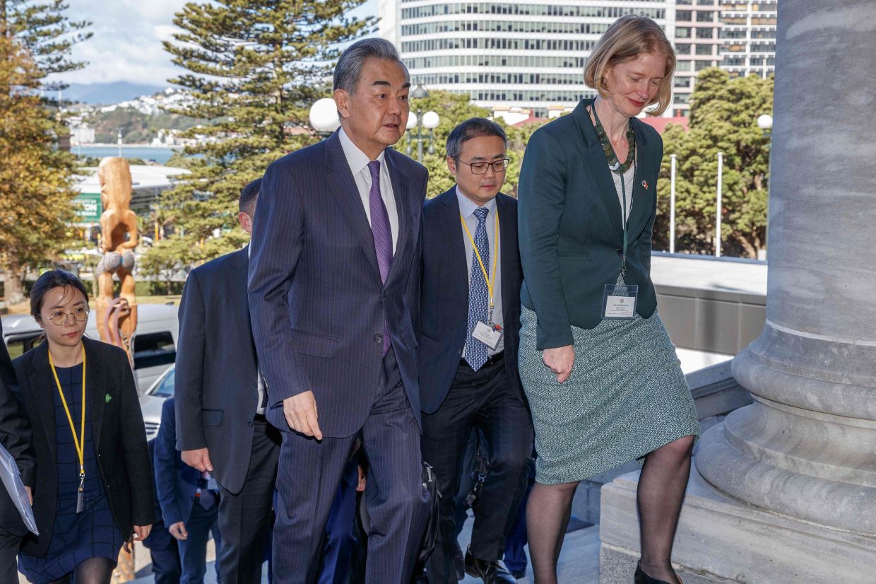 Chinese Foreign Minister Wang Yi (left) is escorted into New Zealand's parliament by Ministry of Foreign Affairs and Trade North Asia divisional manager Wendy Matthews before his bilateral meeting with New Zealand counterpart Winston Peters in Wellington on Monday, March 18, 2024. - AFP