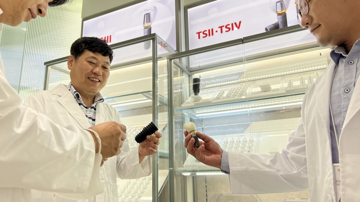 Osstem Implant Research Institute director Yoon Ji-hoon (centre) with his team members at the TS implant exhibition hall. 