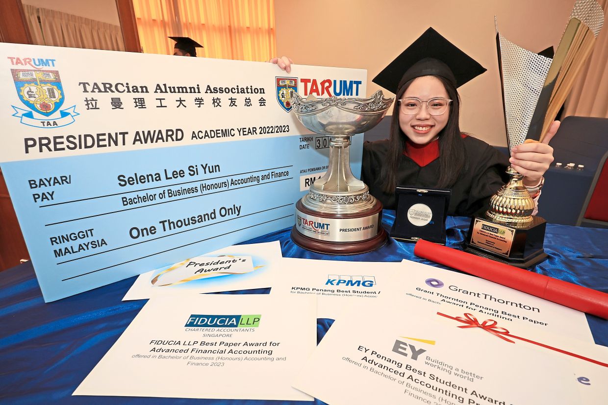 Selena showing her trophy and awards after the graduation ceremony.