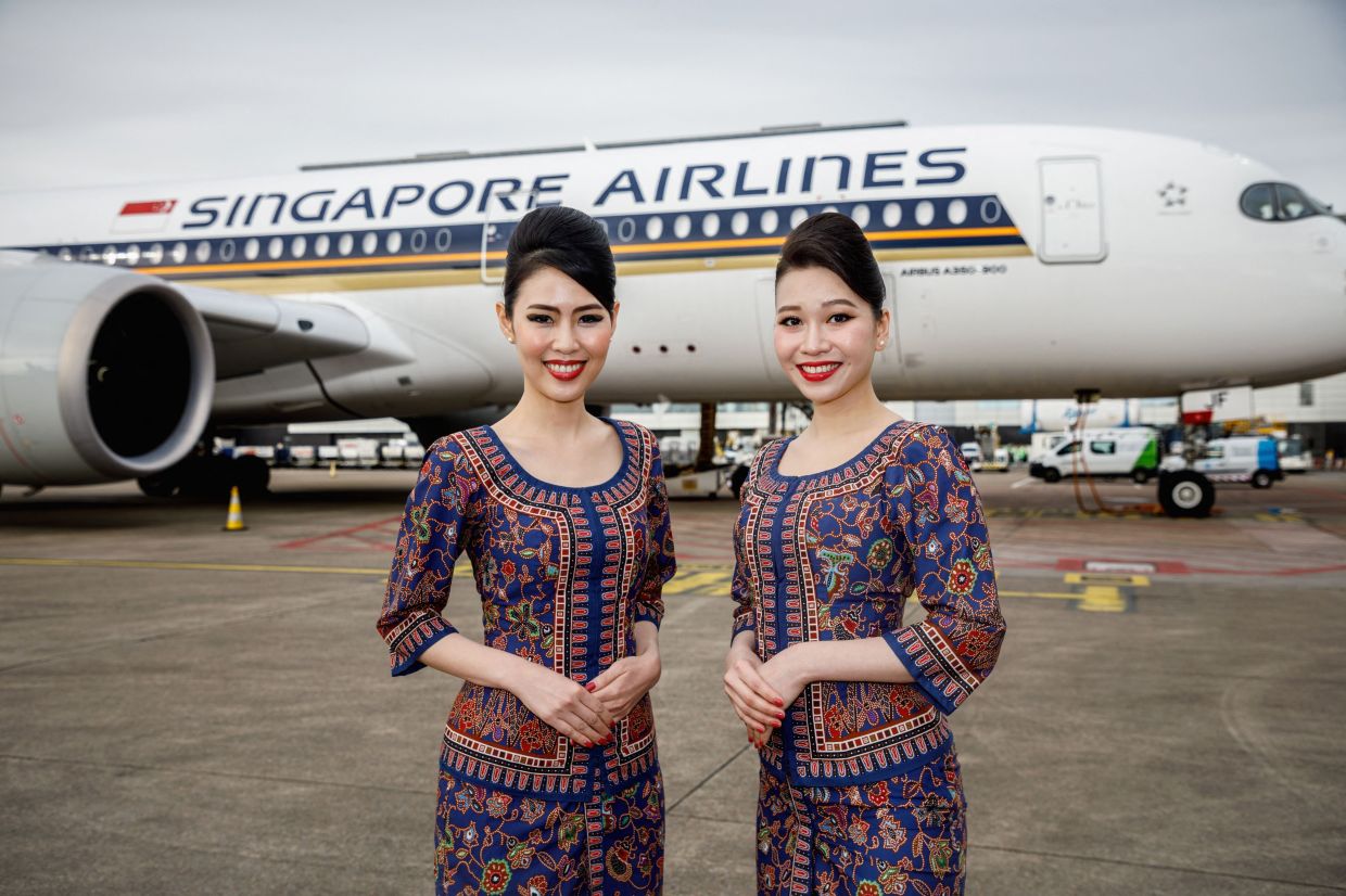 Stewardesses pose in front of an aircraft during a Brussels Airport press briefing to present the launch of a direct flight between Singapore and Brussels departing from Brussels Airport, in Zaventem. - AFP