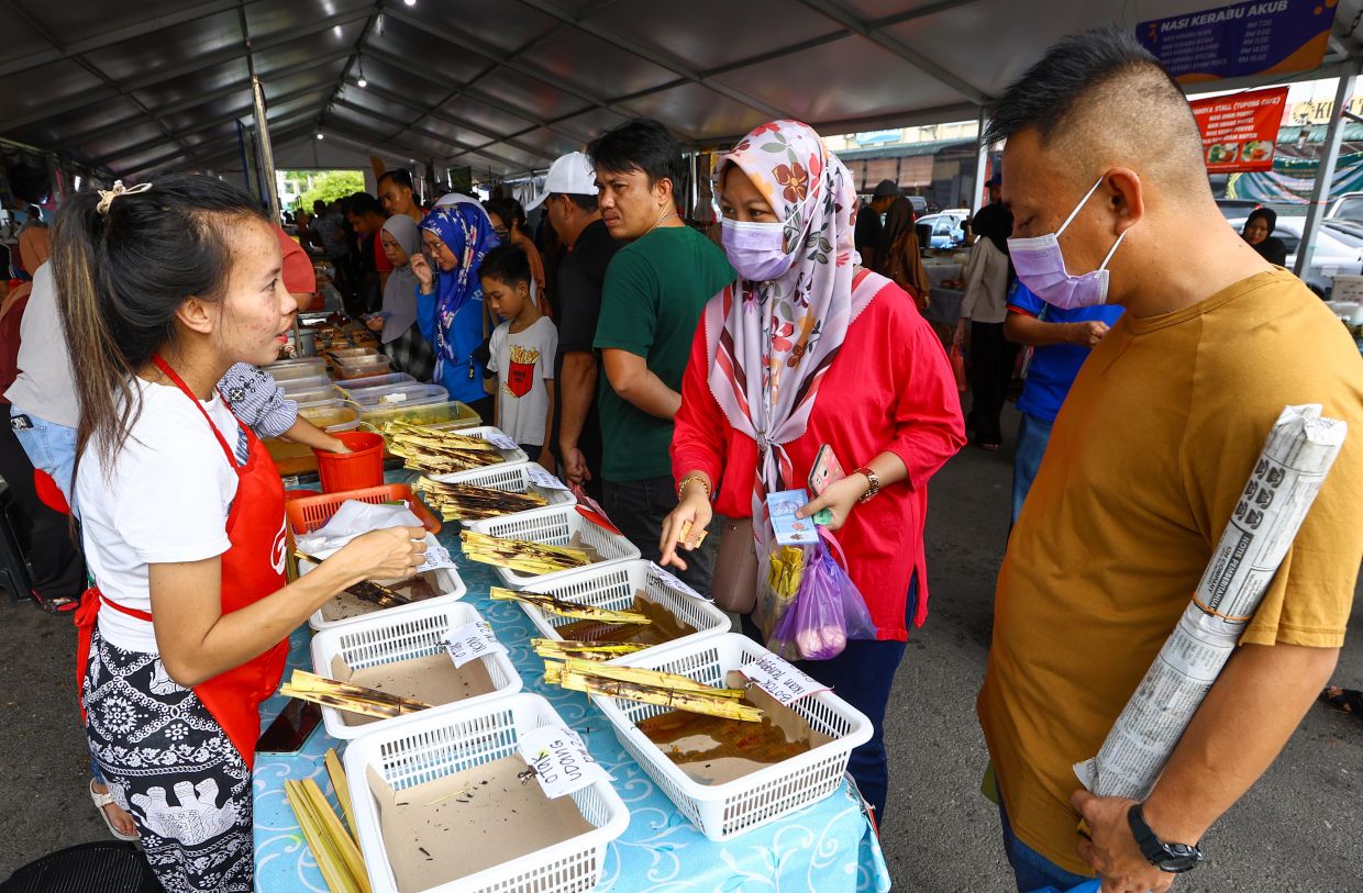 Customers looking at a selection of pais at the Satok Ramadan bazaar in Kuching. - ZULAZHAR SHEBLEE/The Star