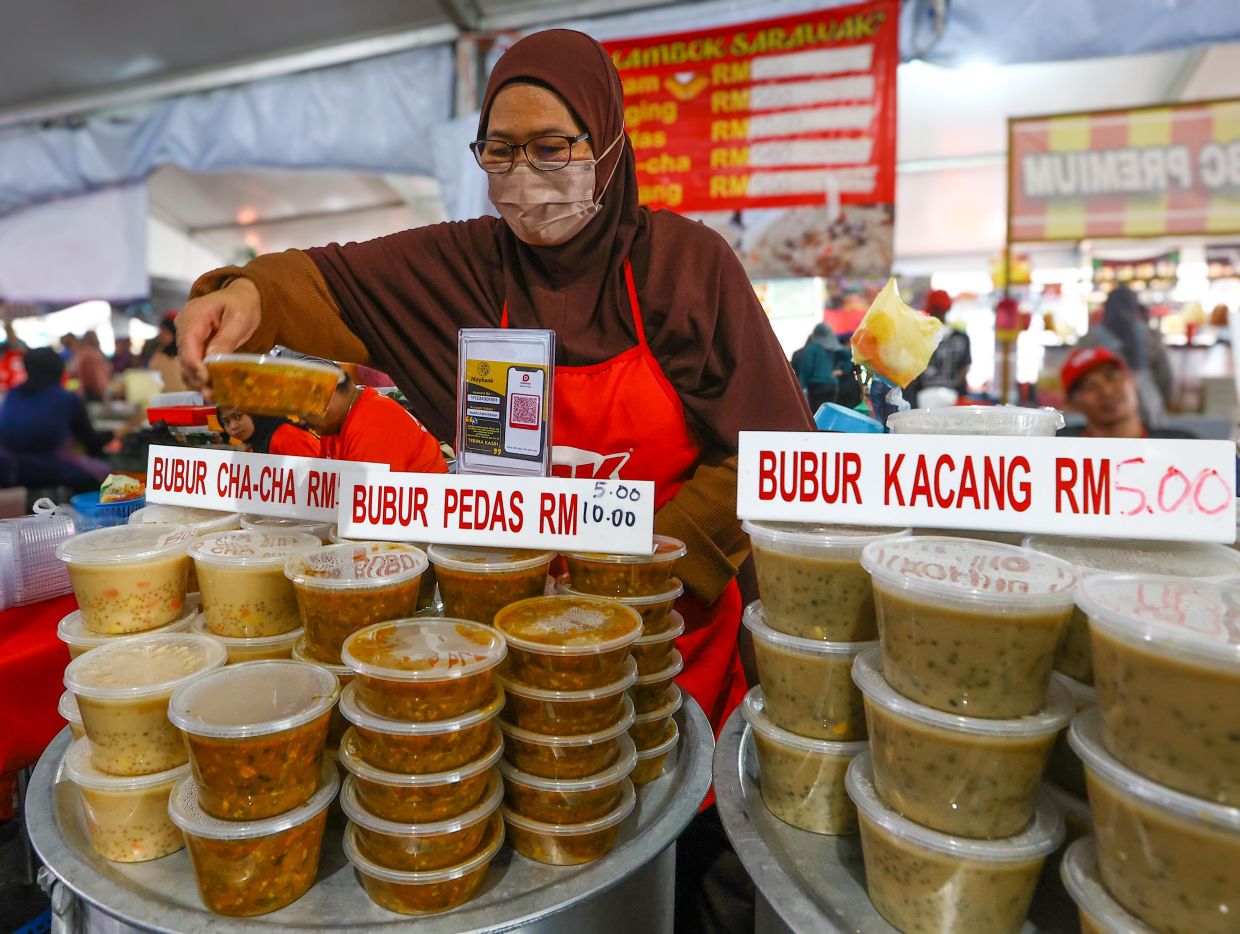 Samnah arranging tubs of bubur pedas at her stall. - ZULAZHAR SHEBLEE/The Star